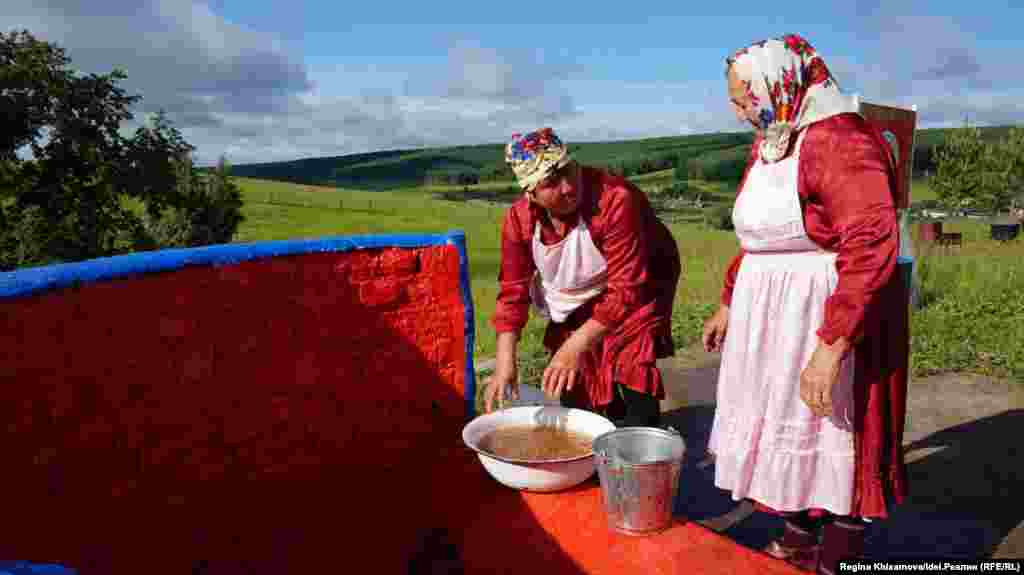 Женщины промывают крупу и мясо в родниковой воде