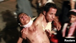 Yemen -- An anti-government protester carries a wounded colleague after clashes with police in the southern city of Taiz, 29May2011